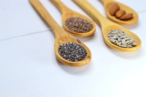 Closeup Photo of Four Brown Wooden Spatulas With Seeds | seed cycling for hormones | flax seeds sesame seeds sunflower seeds and pumpkin seeds