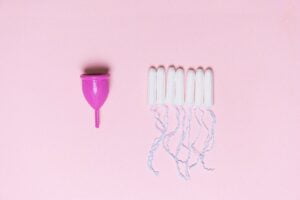 Menstrual cup and tampons arranged on pink surface | Understanding the Luteal Phase