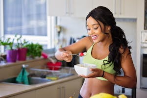 Woman Eating Strawberry in the Kitchen | Not All Breakfasts Are Equal—This One Kickstarts Weight Loss Like No Other | This High-Protein Snack Can Help Lower Your Cholesterol, Say Dietitians