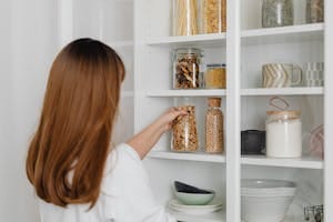 A Woman in White Shirt Holding Clear Glass Jar | cinnamon for fat burning
