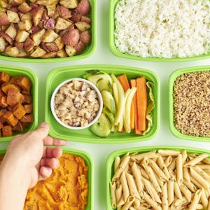 A variety of healthy meals in green containers featuring pasta, rice, and vegetables. | This 2-Step Hack Can Lower Calories in Rice, Potatoes, Pasta and More—Dietitians Say It Works!