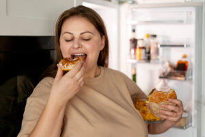 woman eating from fridge | The One Meal You Should Skip for Faster Weight Loss