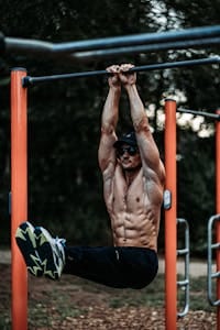 An athletic man exercising on a horizontal bar outdoors, showcasing strength and fitness. | Achieve Chiseled Abs Fast: Why Hanging Core Exercises Are Essential