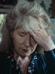 Close-up portrait of a senior woman touching her forehead, eyes closed, expressing sadness. | Turns Out My 'Dementia' Was Just a Vitamin Deficiency—And Fixing It Was So Simple.