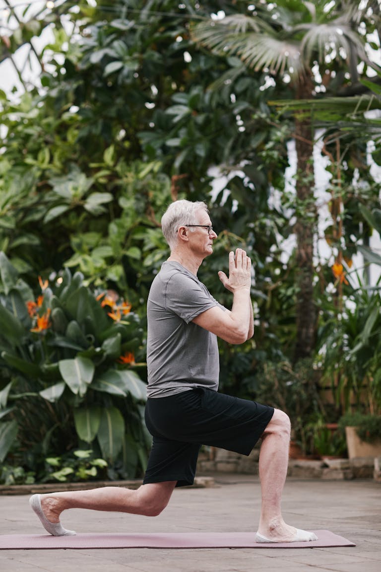 A senior man gracefully performs a yoga pose in a lush botanical garden, embodying mindfulness and well-being. | Fix Your Balance in 10 Minutes—No Gym, No Equipment, No Excuses