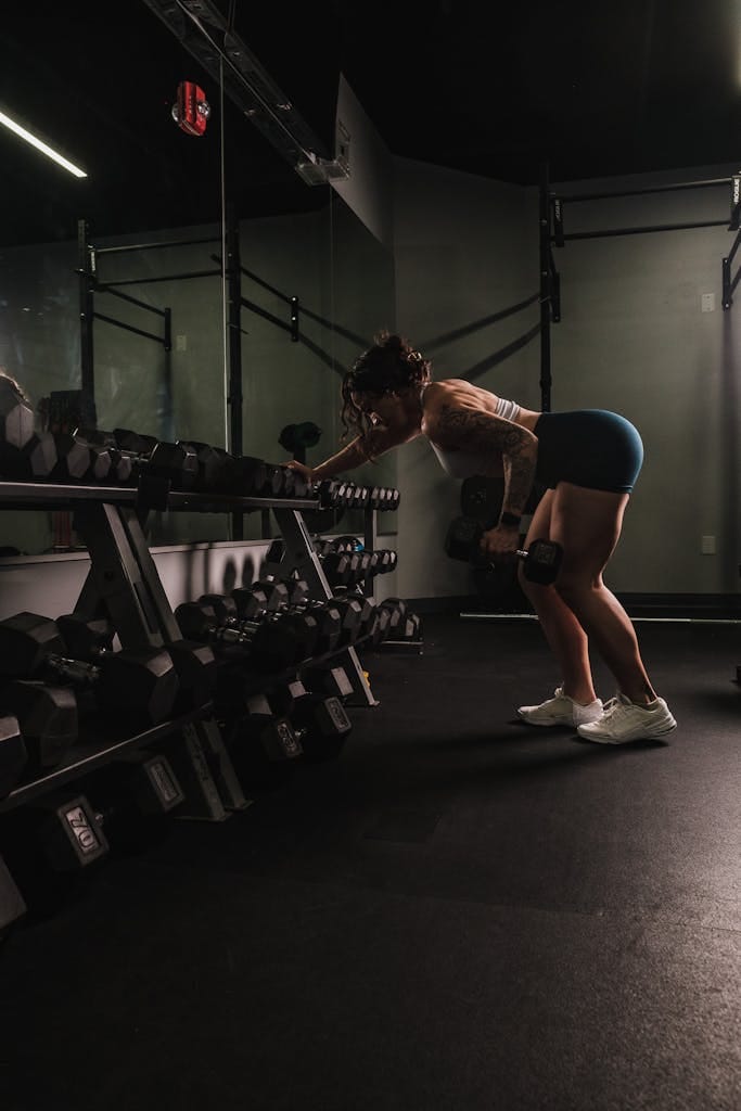 A woman performs a bent-over row with dumbbells in a gym, exemplifying strength and fitness. |