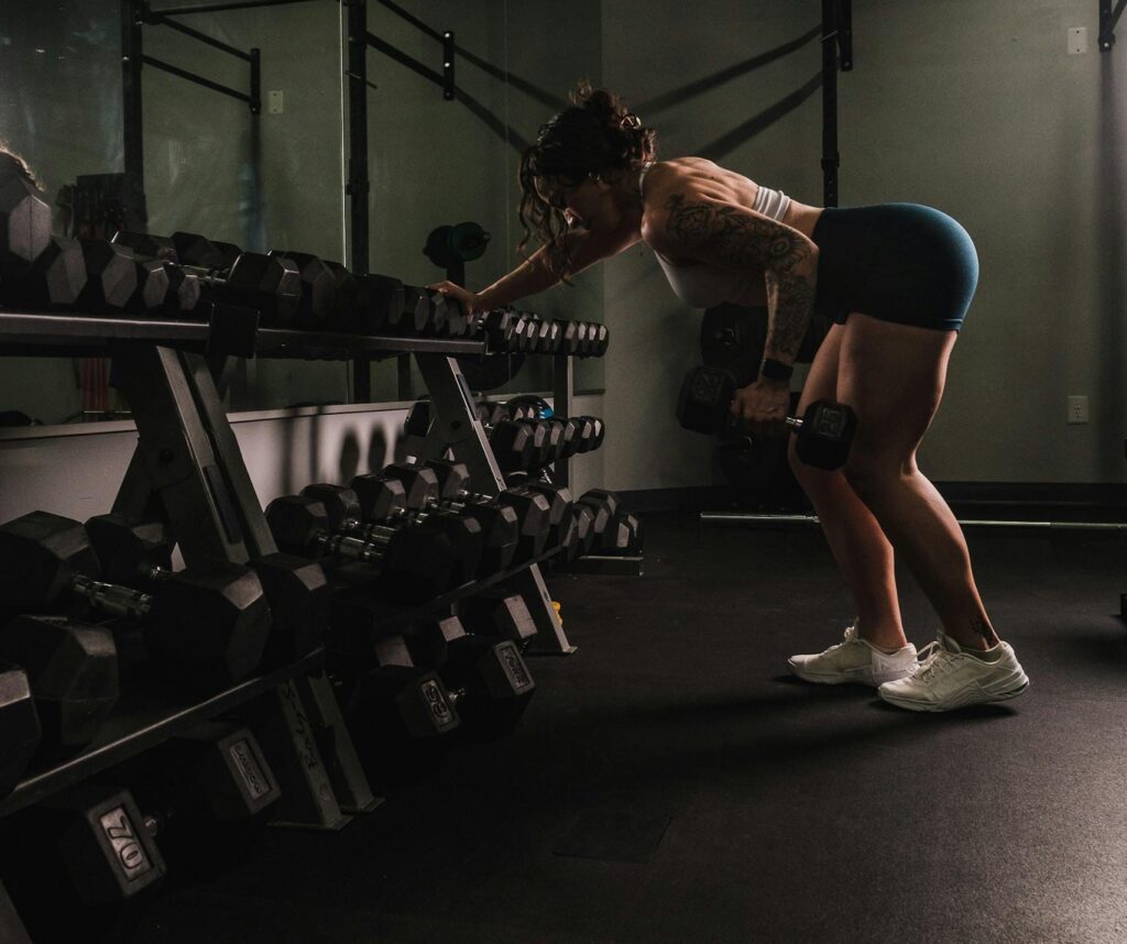 A woman performs a bent-over row with dumbbells in a gym, exemplifying strength and fitness. |