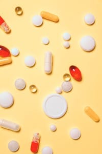 Colorful assortment of pills and capsules on a vibrant yellow background. | Best Vitamin Brands