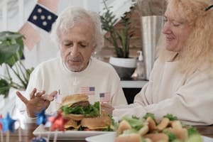 Elderly couple enjoying burgers with American decor, perfect for July 4th celebrations. | Over 50? These 15 Foods Are Practically a Recipe for Dementia