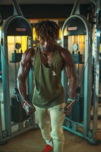 Muscular man performing Cable Shoulder Exercises in a modern gym environment.