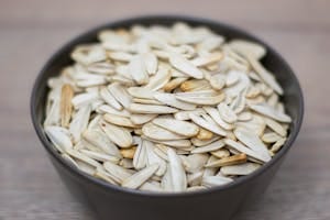 A detailed view of a bowl filled with raw pumpkin seeds. Perfect for healthy snack ideas. | This Seed Packs More Protein Than an Egg and Promotes Sleep (But There's a Catch)