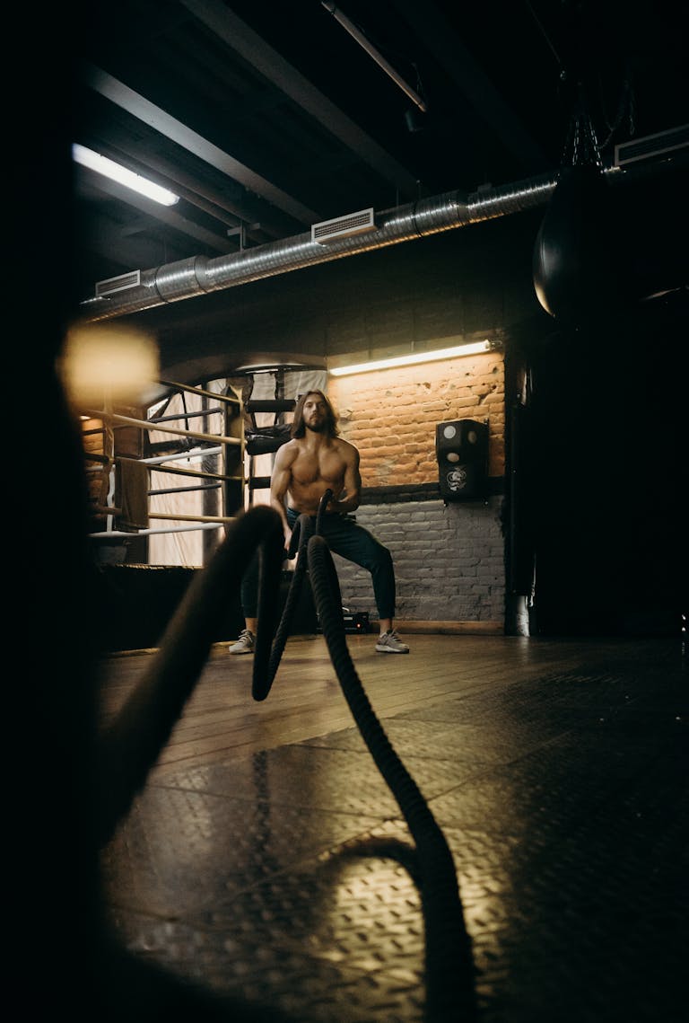 A muscular man showcases strength and endurance during a gym workout using heavy ropes. | Lifting Smarter, Not Harder: How to Build Muscle Nearly 2x Faster