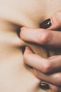 Artistic close-up of a hand pinching skin revealing manicure details.