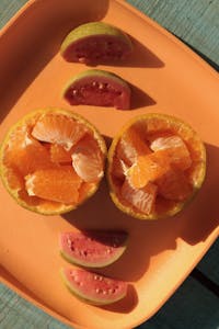 Close-up of citrus and guava fruit slices on a vibrant orange plate for a healthy, tropical snack. | The 10 Fruits with the Most Protein (Yes, Fruits Can Be Protein-Packed!)
