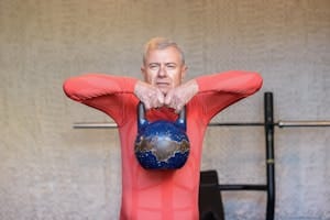 Elderly man engages in strength training with kettlebell, promoting fitness and healthy aging. | Defy Age: 13 Surprising Tips Making 60-Year-Olds Stronger Than Millennials | 5 Daily Exercises That Double Grip Strength and Reverse Aging.