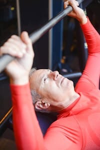 Elderly man lifting barbell in gym promotes healthy lifestyle and strength. | At 82, He’s Still Hitting the Gym—And Says This Diet Is the Reason | longevity exercise
