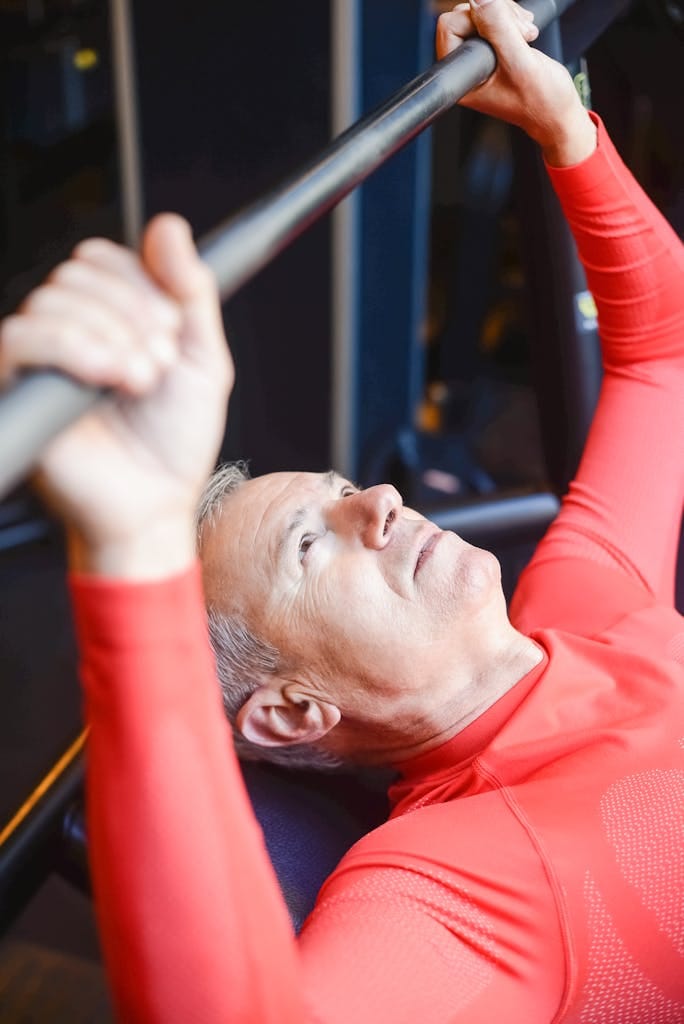 Elderly man lifting barbell in gym promotes healthy lifestyle and strength. | At 82, He’s Still Hitting the Gym—And Says This Diet Is the Reason | longevity exercise