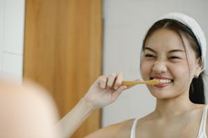 Smiling woman with toothbrush reflects joyful wellness morning routine. | Defend Your Smile: Top Cavity Prevention Tips and Risk Factors