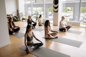 Women of various ages practice yoga meditation indoors in a serene studio. | Maximize Your Gains with This Simple Breathing Technique | diaphragmatic breathing