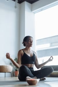 Young woman practicing yoga and mindfulness indoors, embracing tranquility and peace.