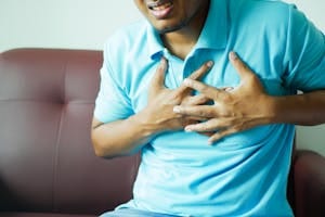A close-up image of a man clutching his chest, indicating heart pain or discomfort. | 10 Healthy Snacks That Might Be Silently Wrecking Your Heart After 60