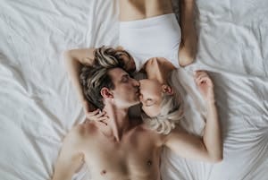 A couple sharing an intimate kiss while lying side by side on a bed. | Boost Your Stamina: The Best Drinks to Keep You Going All Night