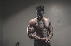 A strong, shirtless male bodybuilder showcasing muscles and strength in a gym setting. | Transform Your Grip and Forearms with These No-Equipment Home Workouts | Most Gym-Goers Do These Triceps Moves Wrong—Here’s the Smarter Way to TrainStrength Training Timing: How Long Before You See Real Gains?