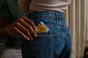 Condom being placed into denim jeans pocket, emphasizing safe sex and contraceptive use. | Edging, Exercise and Other Ways to Prevent Premature Ejaculation