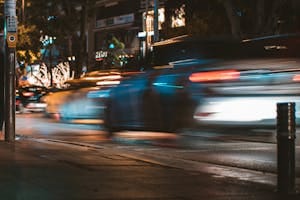 Long exposure capture of urban traffic showcasing light streaks and busy city life at night. | Night Driving Got You Nervous? 7 Expert Tricks to See Better After Dark