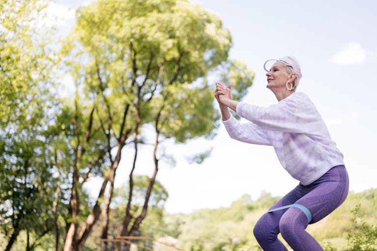 A senior woman exercises in a park with a resistance band, embracing a healthy lifestyle. | Weak Balance? This 7-Minute Routine Strengthens Stability Better Than Yoga (No Mat Required)