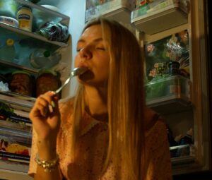 A woman savoring cake while sitting in front of an open refrigerator at night. | The Midnight Snack That's Quietly Destroying Your Gut Health | The "Forbidden" Nighttime Bites: 6 Foods Nutritionists NEVER Eat Before Bed (Sleep Better, Lose Weight!)