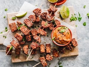 Appetizing grilled tempeh skewers paired with a rich, spicy peanut sauce, garnished with fresh herbs. | I Ditched Meat for These 9 Plant Proteins—One Has Even More Protein Than Chicken