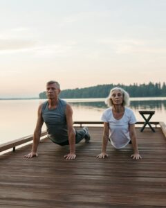 Elderly couple performing yoga outdoors by a serene lake. | Age Reversal Workout: This "Slow-Mo" Method Builds Strength & Fights Muscle Loss (Even at 70+!)