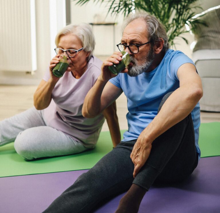 Elderly couple relaxing with green smoothies, embracing positive aging and healthy living indoors. | 10 Slimming Smoothies Seniors Love for a Flatter Belly and Happier Gut