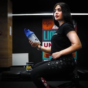 Fitness enthusiast in sportswear holding a shaker bottle indoors at the gym. | Creatine for Women: The Surprising Benefits (Hint: It’s Not Just for Muscle)