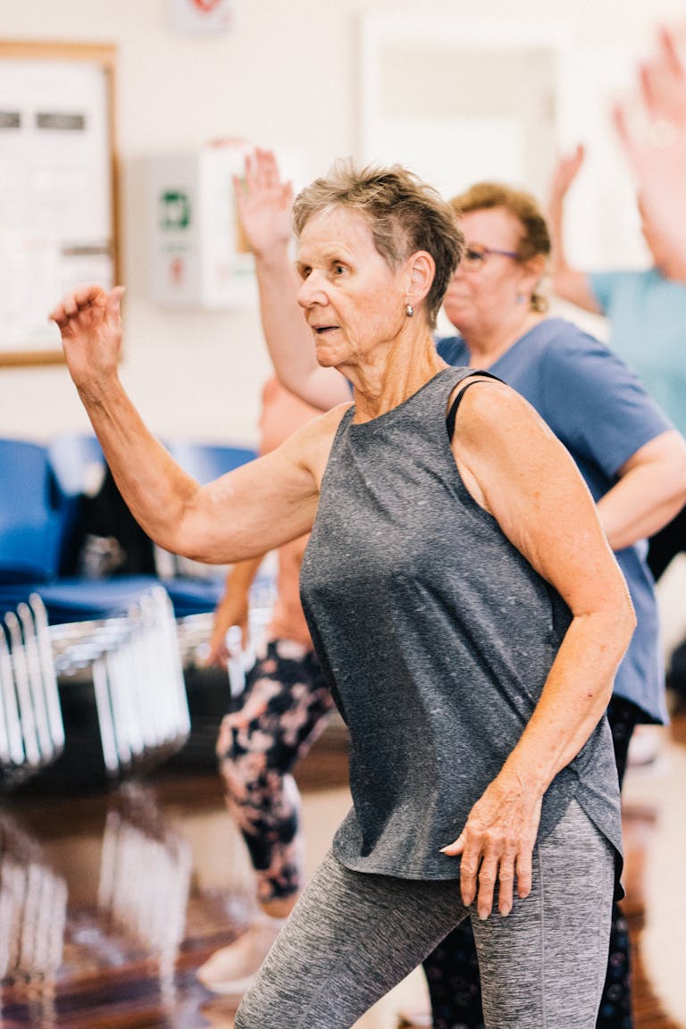 Group of senior women dancing energetically in a fitness class promoting a healthy lifestyle. | Want to Live to 100? Experts Share 10 Game-Changing Habits You Can Start Today