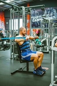 Man working out with resistance bands in a modern gym setting. | Skip the Weights: This Chair Workout With Resistance Bands Toned Me Fast