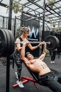 Muscular man and woman weightlifting at a modern Mexico City gym. | Can You Double Your Bench Press in 30 Days? Here’s Exactly How to Find Out