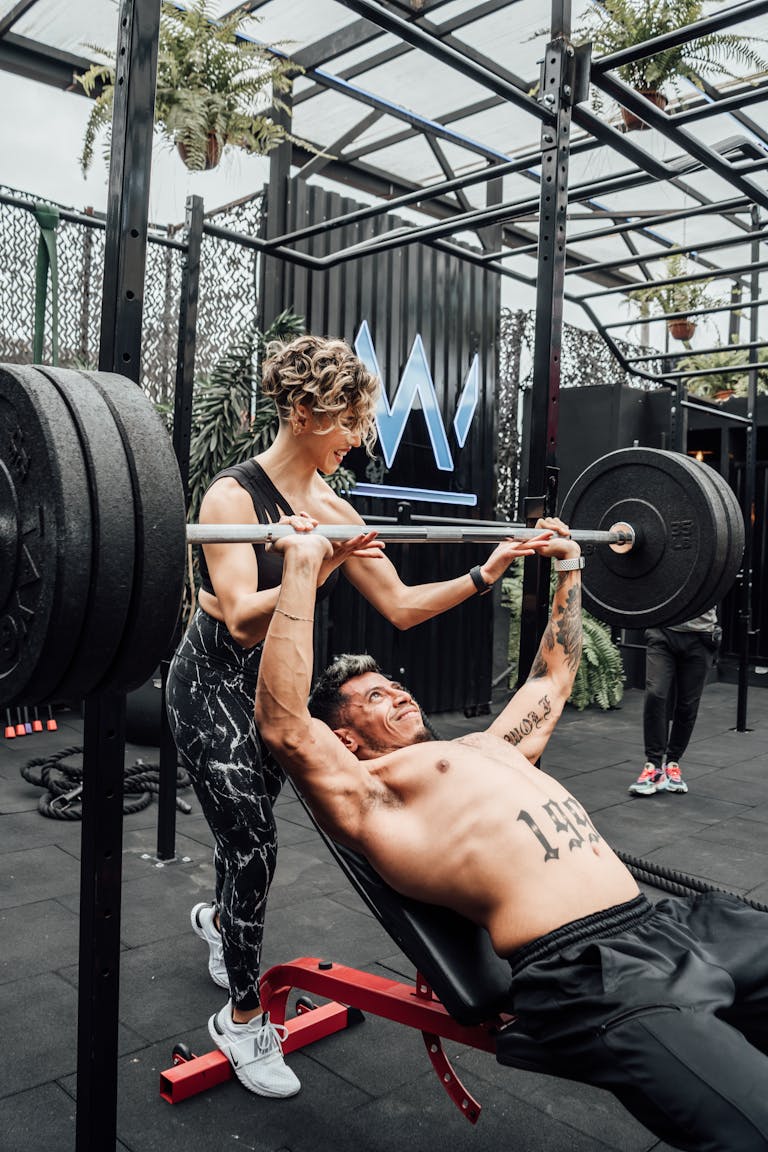 Muscular man and woman weightlifting at a modern Mexico City gym. | Can You Double Your Bench Press in 30 Days? Here’s Exactly How to Find Out