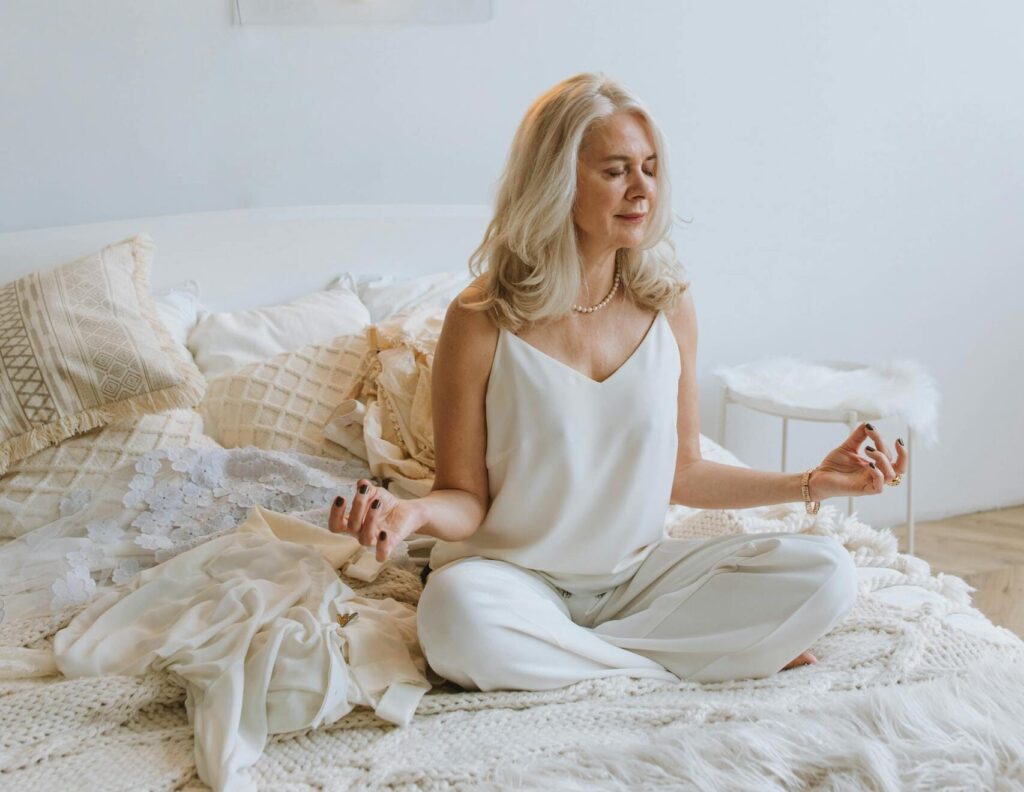 Serene woman meditating on a cozy bed under 'Good Vibes Only' neon sign. | Master Your Morning: 5 Expert Habits for Stable Blood Sugar All Day