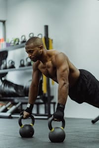 Shirtless African American man performing kettlebell push-ups in the gym. | Skip the Bench Press: These Forgotten Upper Chest Exercises Ignite Serious Growth
