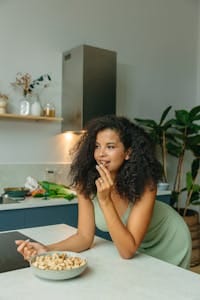 Woman enjoying a healthy snack in a stylish kitchen ambiance. Perfect lifestyle moment. | Want to Lose Weight? Dietitians Say THIS Is The #1 Nut You Need