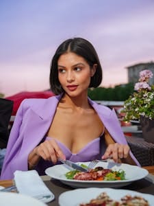 Young woman enjoying an elegant seafood dinner at a beautifully set outdoor restaurant. | Stop Heart Attacks Before They Start—These 10 Foods Are the Key