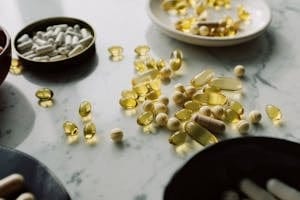 A close-up of assorted pills and supplements arranged on a marble surface, highlighting healthcare and wellness themes. | Big Beauty’s Dirty Secret: The Skincare Vitamin Linked to Liver Failure