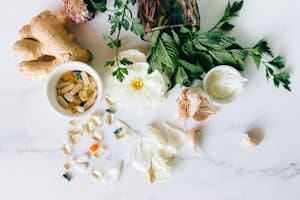 A flatlay of herbal supplements with fresh ginger, garlic, and leaves. | Nature’s Ozempic? 5 Herbs That Burn Fat and Help You Lose Weight Naturally, Says One Doctor