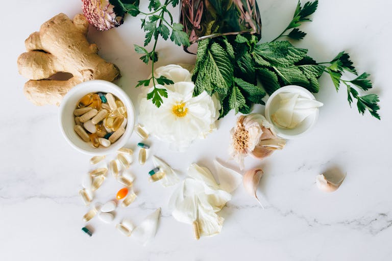 A flatlay of herbal supplements with fresh ginger, garlic, and leaves. | Nature’s Ozempic? 5 Herbs That Burn Fat and Help You Lose Weight Naturally, Says One Doctor