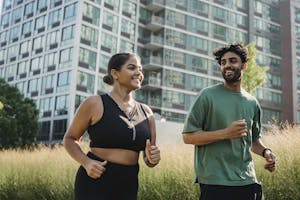 A joyful couple jogging in a city park, promoting a healthy lifestyle. | The Metabolism ‘Sweet Spot’: Walk This Many Steps Daily to Burn Fat While You Sleep