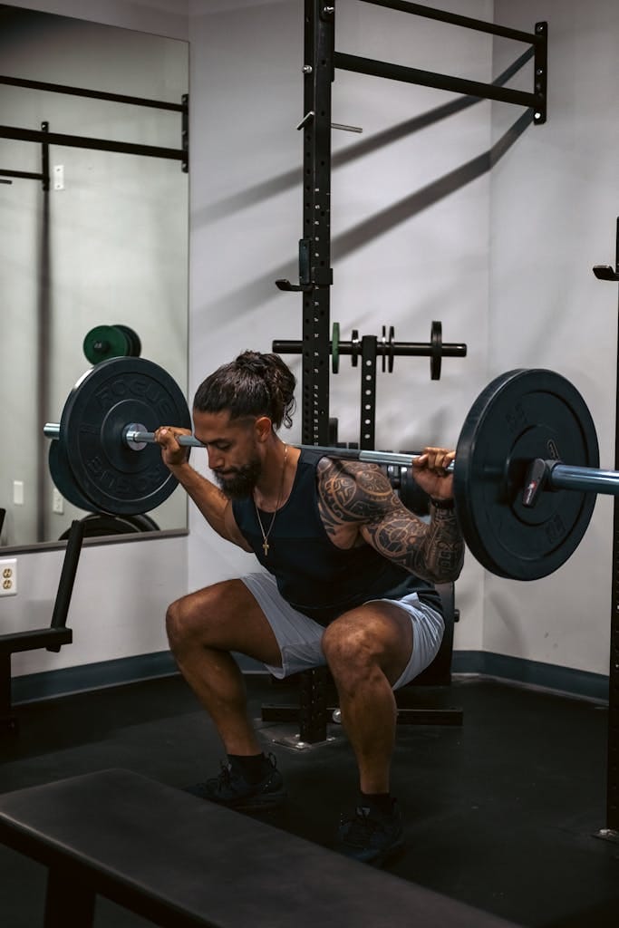 A tattooed man performing a squat with a barbell, emphasizing strength and fitness. | Unlock Rapid Gains: The PROVEN Pyramid Training Secret for Explosive Muscle & Strength!
