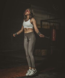 Athletic woman in activewear jumps rope in a gym setting, showcasing fitness and determination. | Can Jumping Actually Strengthen Your Bones? Here’s What Doctors Say