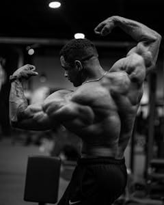 Black and white photo of a bodybuilder flexing muscles indoors. | Unlock HUGE Gains: This is The ONLY Pull Workout You'll Ever Need for Massive Muscle